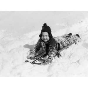  Girl in Wool Knit Hat and Snow Suit Laying Down on Sled 